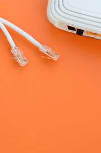 High angle view of computer cable and router on orange background