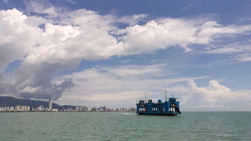 Penang ferry on sea against cloudy sky