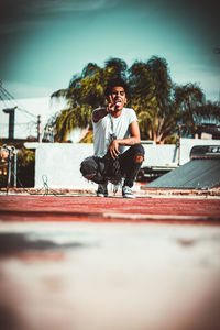 Full length of man sitting in city against sky