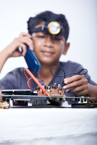 Schoolboy holding a landline phone and voltmeter to studying electronic telecommunication