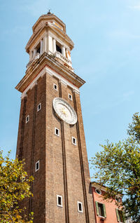 Low angle view of clock tower amidst buildings against sky