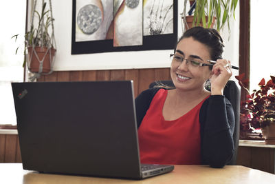 Smiling woman using laptop on table at home