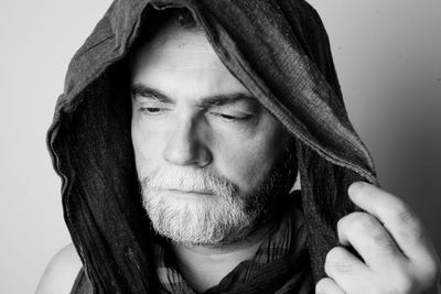 Close-up of man wearing hood against white background