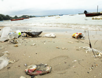 Garbage on sand at beach against sky