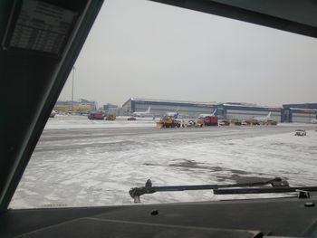 Airplane on runway against sky seen through window