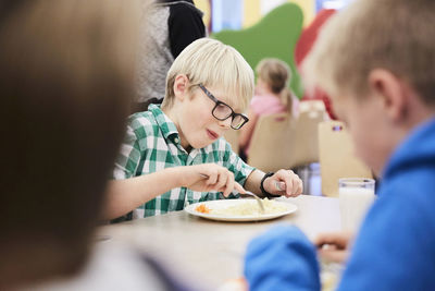 Boy having lunch at table in school cafeteria