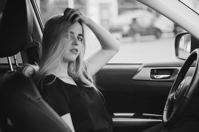 Portrait of beautiful young woman sitting in car
