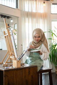 Portrait of young woman using mobile phone while sitting at home