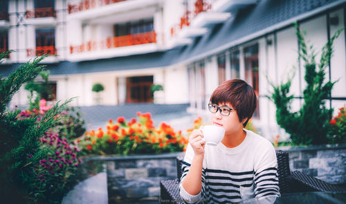 Young woman with flowers in front of building