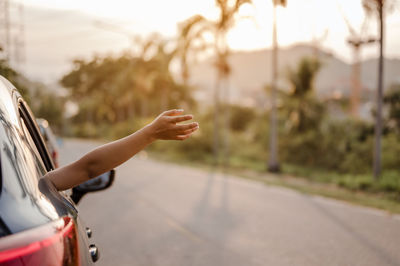 Cropped image of woman waving hand out of car