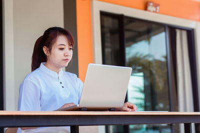 Young woman using mobile phone while sitting on table