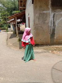 Full length of girl standing on road against house