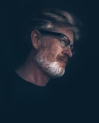 Portrait of man wearing eyeglasses against black background