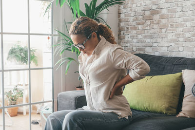 Young woman using laptop while sitting on sofa at home