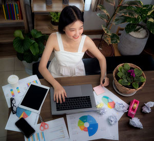 Young woman using phone while sitting on table