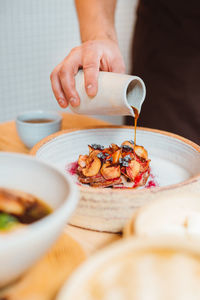 Vertical view of the unknown man hand pouring maple syrup on baked apples