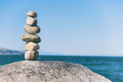 Stack of stones in sea against sky