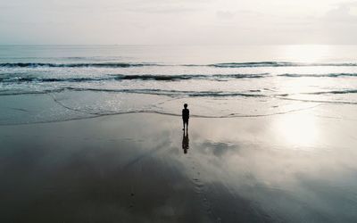 Rear view of boy standing at sea shore 