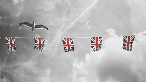 Low angle view of flags flying against sky