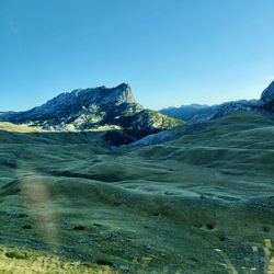 Scenic view of landscape and mountains against clear blue sky