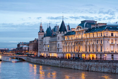 Conciergerie scenic castle in paris over river in the city. view from pont neuf at sunset