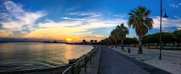 Promenade by lake against sky during sunset