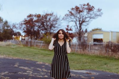 Portrait of beautiful woman standing on road during sunset