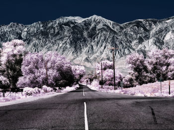 Road amidst trees and mountains against sky