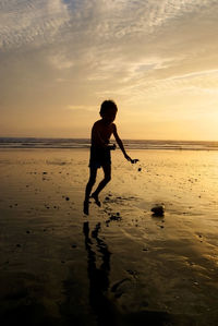 Full length of silhouette man on beach against sky during sunset