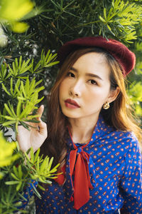 Portrait of smiling young woman standing against tree