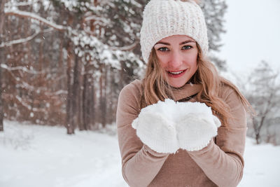 Christmas, holidays and season concept. young happy woman blowing snow in the winter forest nature.