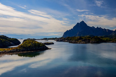 Scenic view of sea by mountain against sky