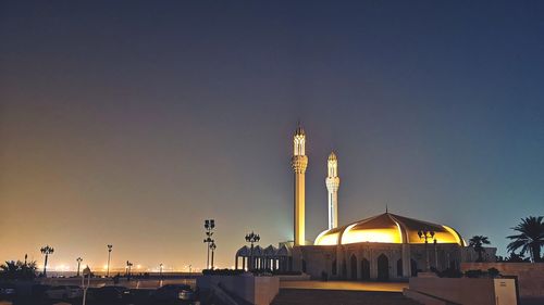 Illuminated building against clear sky at sunset