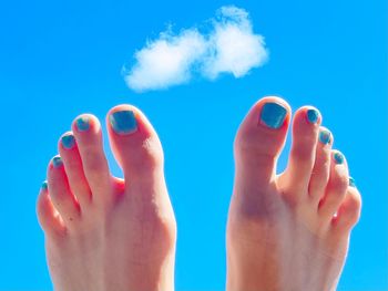 Low section of woman legs against blue sky