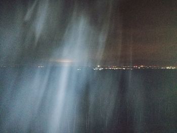 Aerial view of illuminated sea against sky