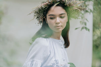 Portrait of beautiful young woman standing against plants