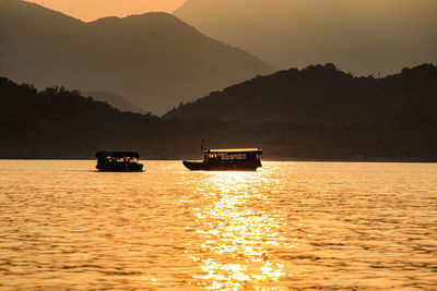 Silhouette boat sailing on sea against sky during sunset