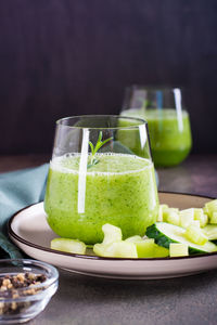 Fresh green cucumber and celery smoothie in glass for vegetarian diet vertical view