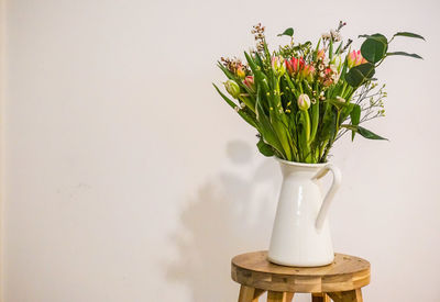 Close-up of flower pot on table against wall