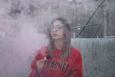 Portrait of young woman in pink smoke