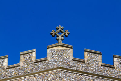 Low angle view of sculptures on building against blue sky