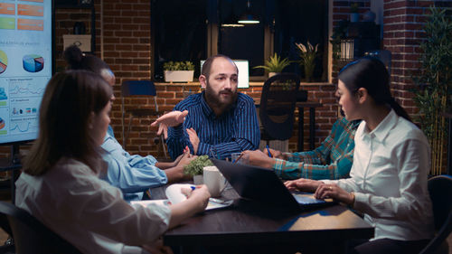 Friends using digital tablet while sitting on table