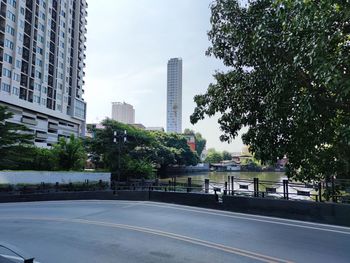 Road by buildings in city against sky