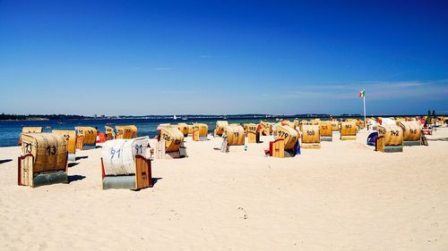 Hooded beach chairs on sandy beach against blue sky in heikendorf