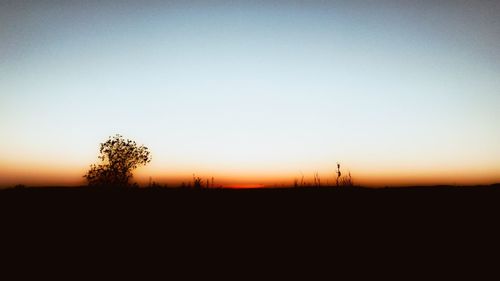 Scenic view of silhouette field against clear sky during sunset