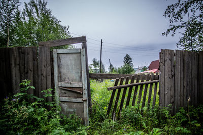 Old house by trees against sky