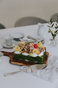 Swedish sandwich cake with shrimps, cheese, ham and eggs on wooden board at table