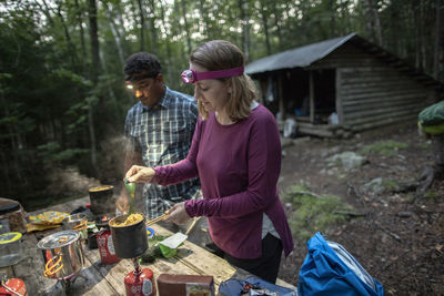 Couple with headlamps cook in front of appalachian trail shelter maine