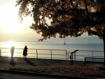 Silhouette people by sea against sky