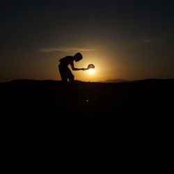 Silhouette man standing against sky during sunset